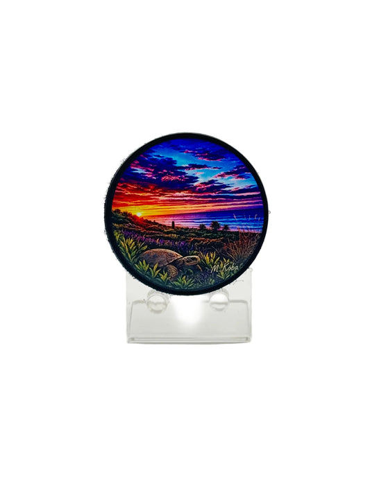 A circular embroidered patch featuring a colorful sunset landscape with a turtle in the foreground, 